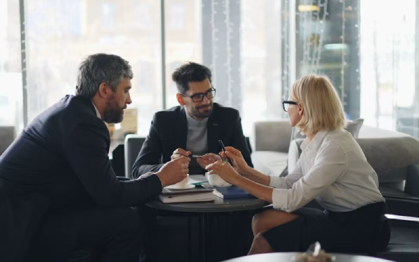 Three colleagues in a business meeting discussing documents at a table